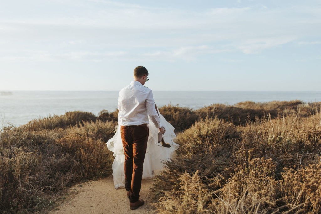 bride and groom walking on coast in big sur