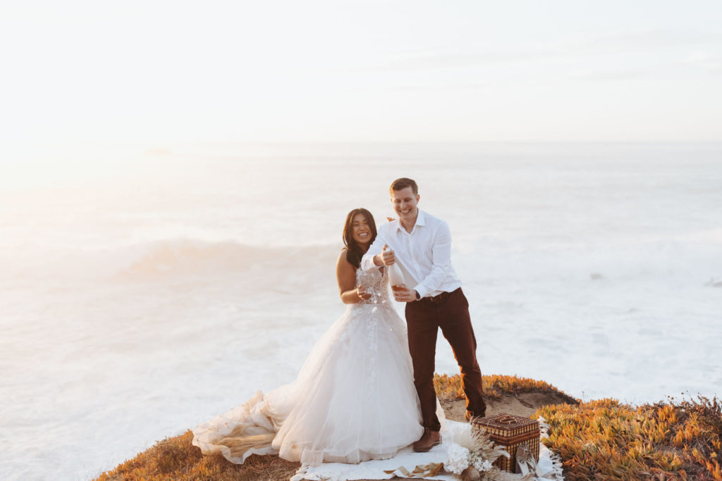 bride and groom popping champagne at big sur elopement picnic