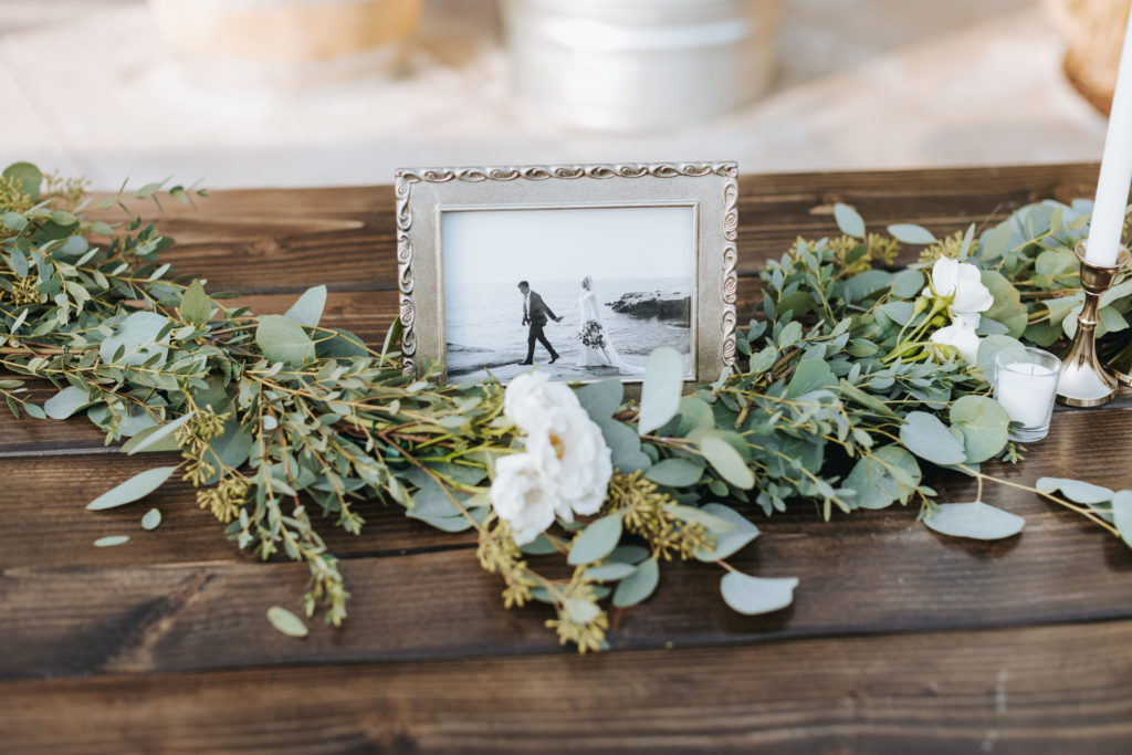 temecula wedding reception table decor with greenery and photo frame