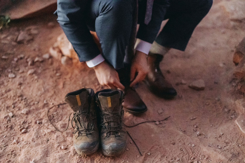 groom putting on hiking boots in cathedral rock