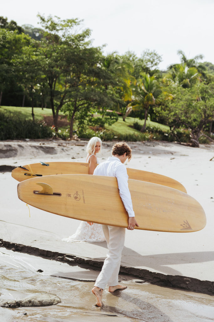 bride and groom holding surfboards in costa rica