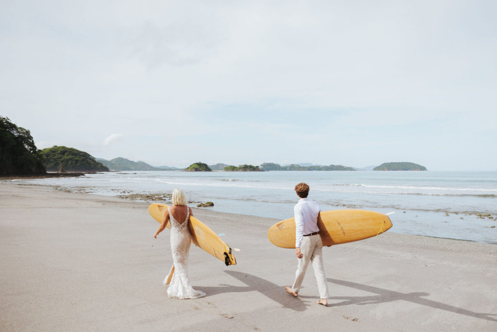 bride and groom holding surfboards in costa rica