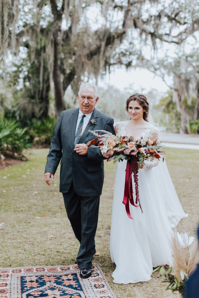 bride walking down aisle with father in boho wedding