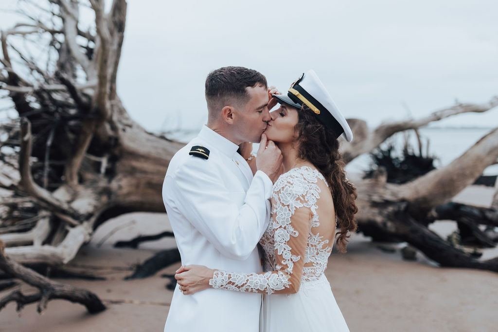 bride wearing groom's military hat on the beach