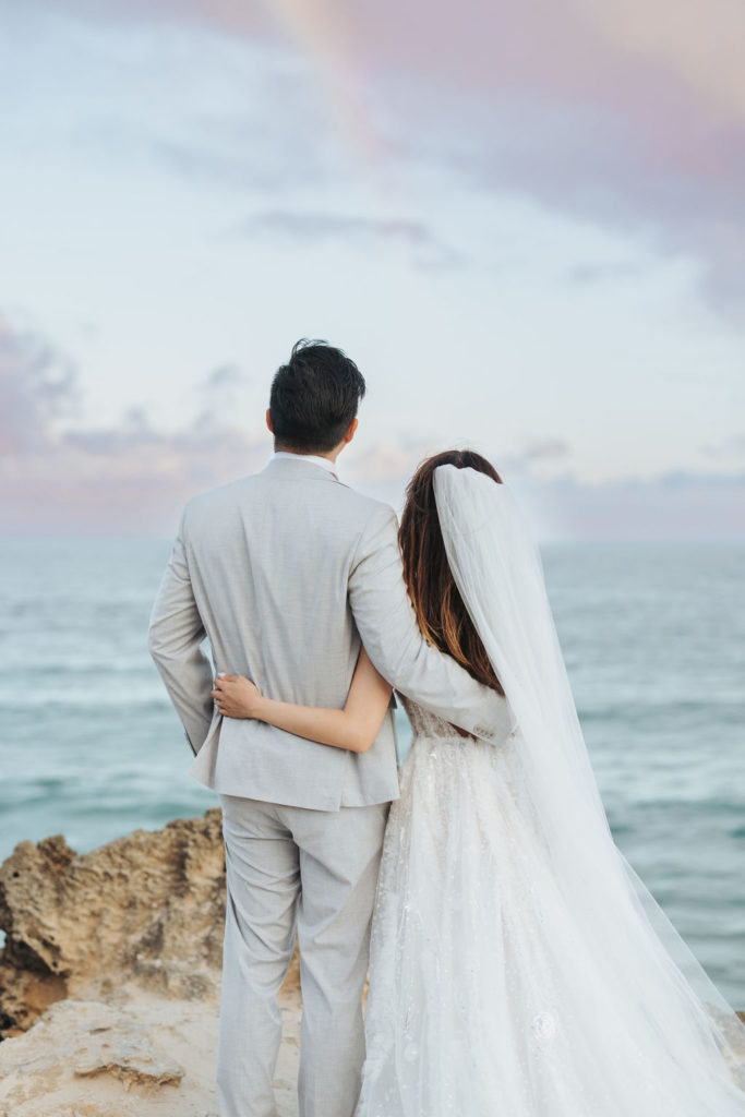 bride and groom looking over ocean in beach portraits in kauai hawaii