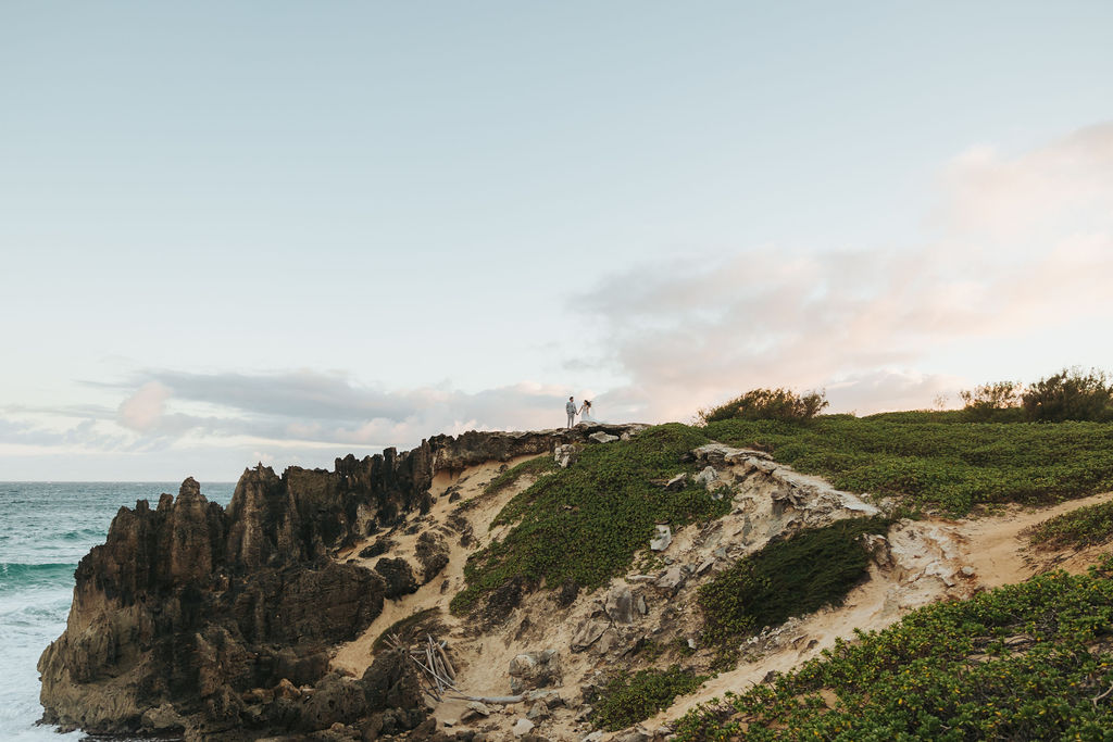 bride and groom standing on rocky hawaii coast
