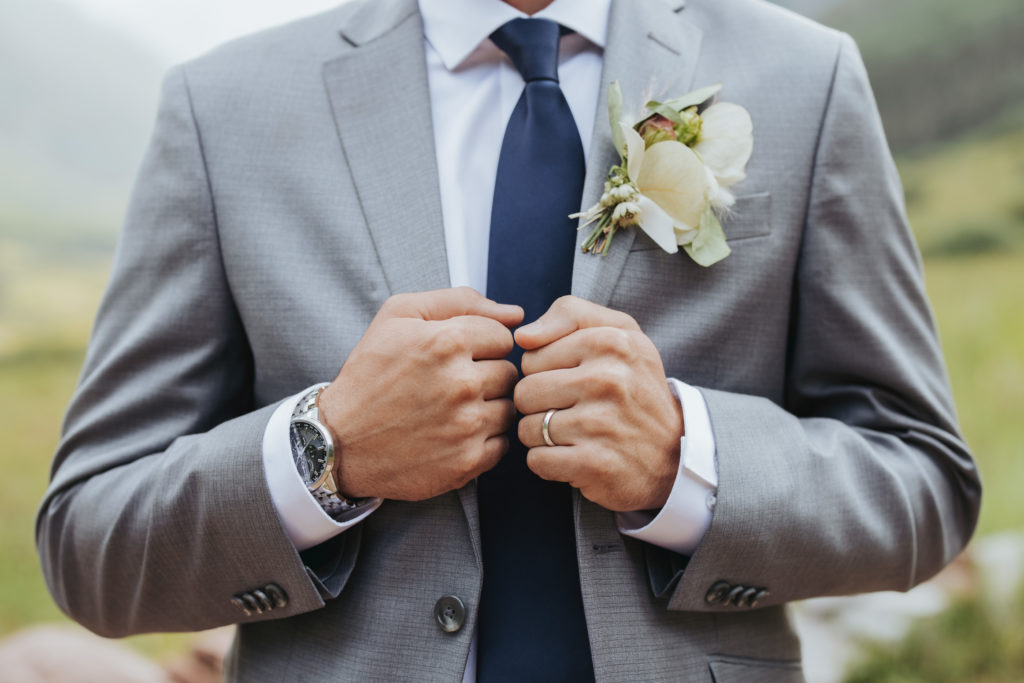 groom in gray suit navy tie and white boutonniere