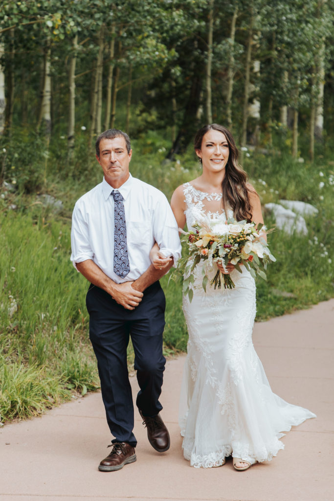 bride walking with father at colorado wedding ceremony