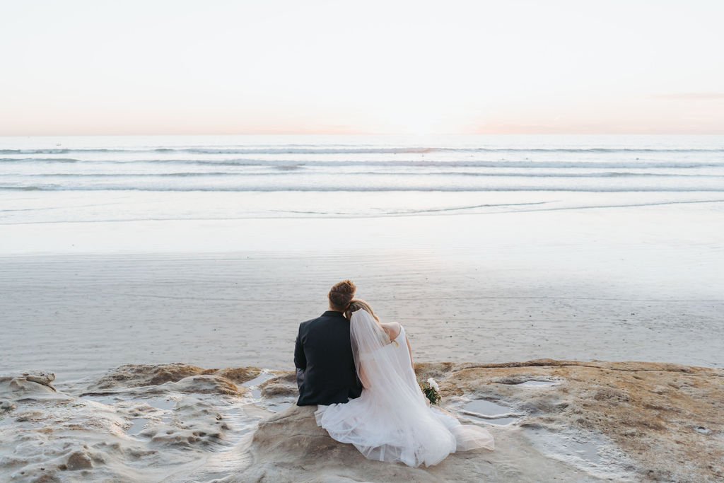 bride and groom looking out over california beach