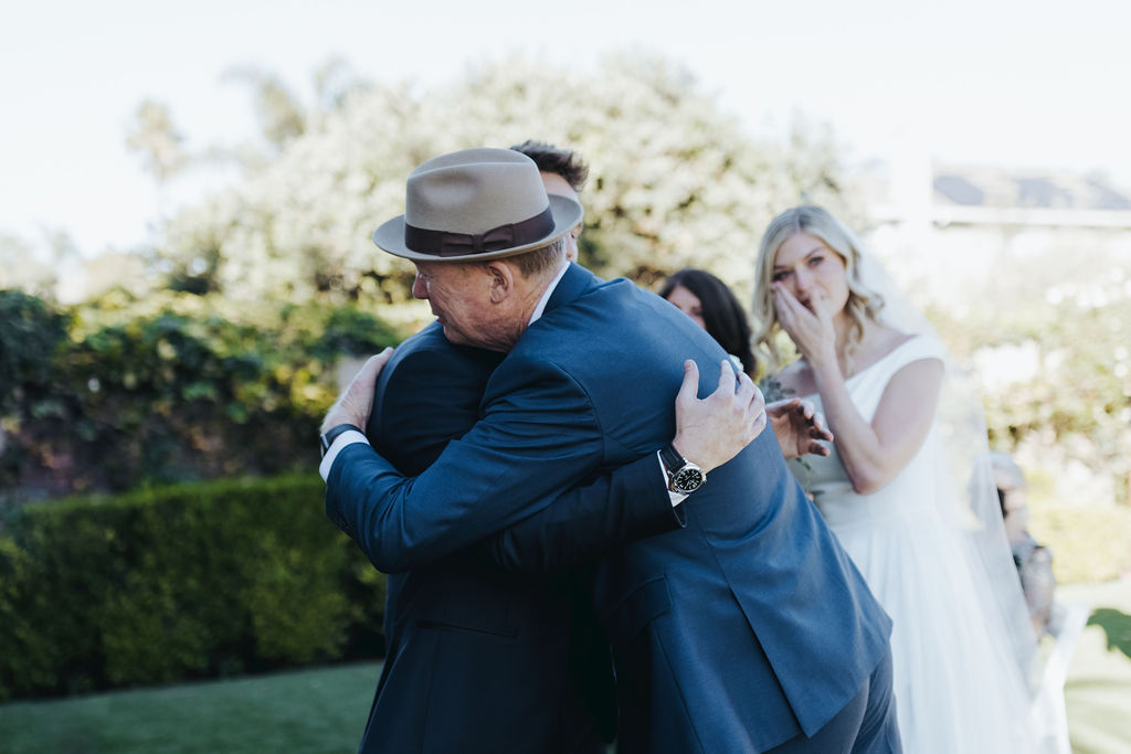 groom hugging bride's father during wedding ceremony