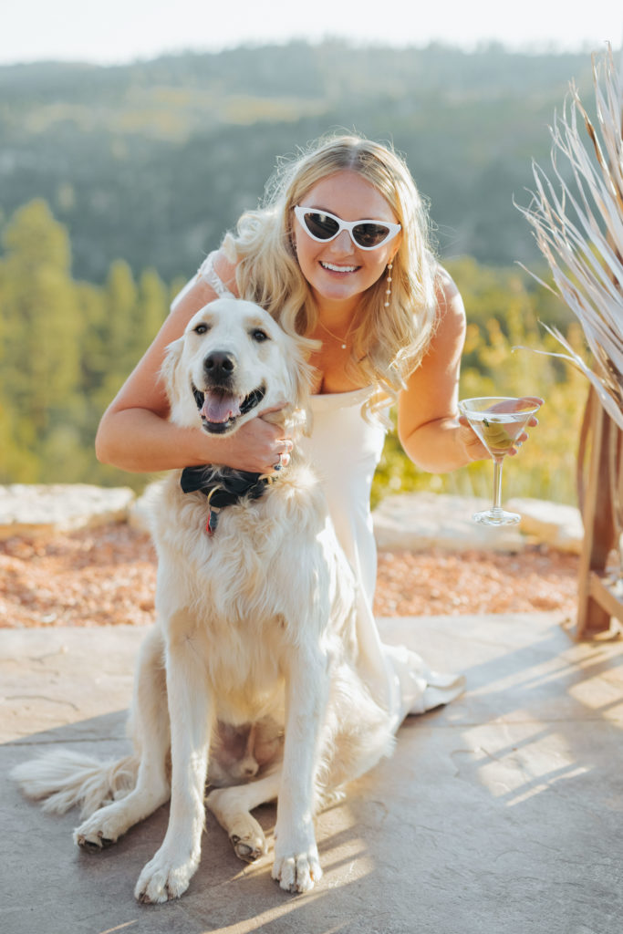bride wearing sunglasses and drinking martini as she hugs dog