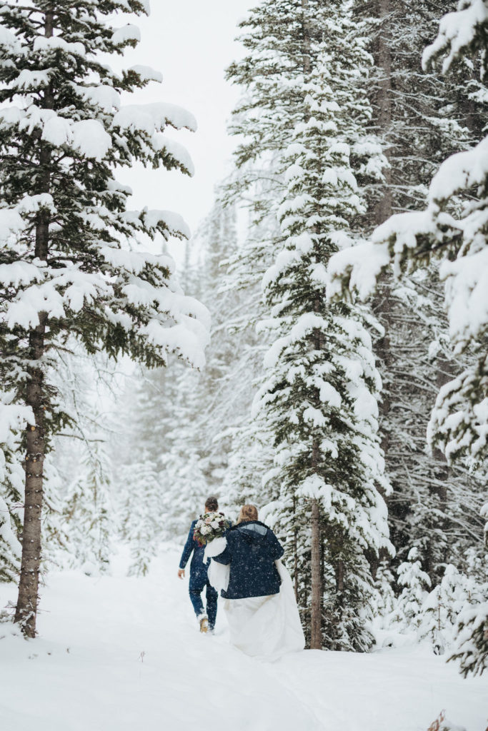 bride and groom walking in snowy trees