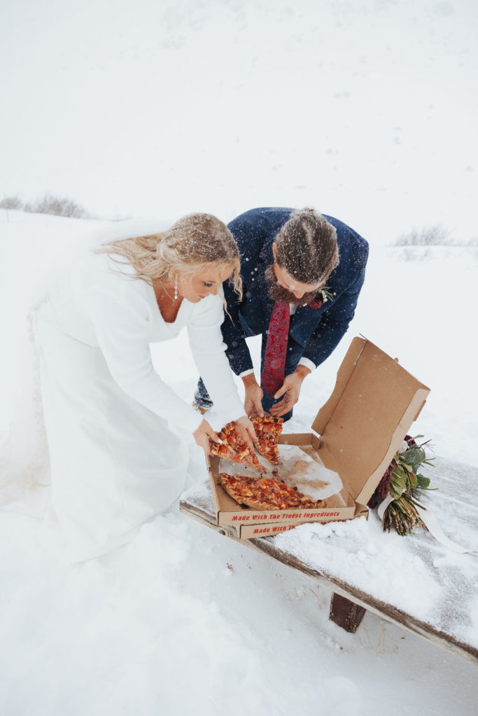 bride and groom eating pizza in the snow