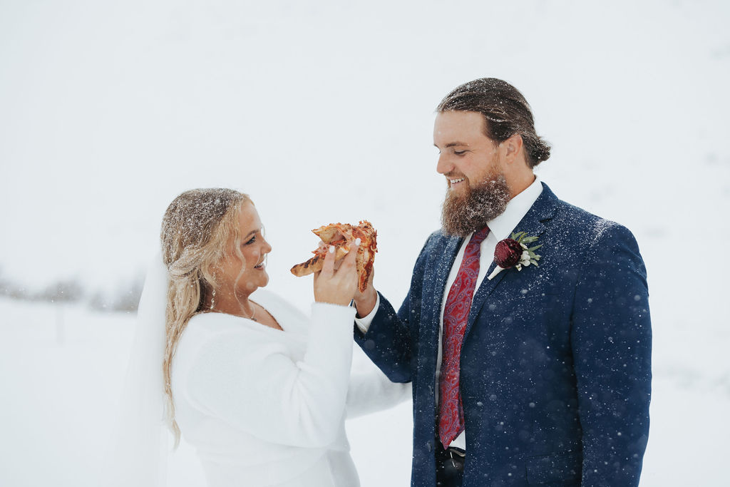 bride and groom eating pizza in the snow