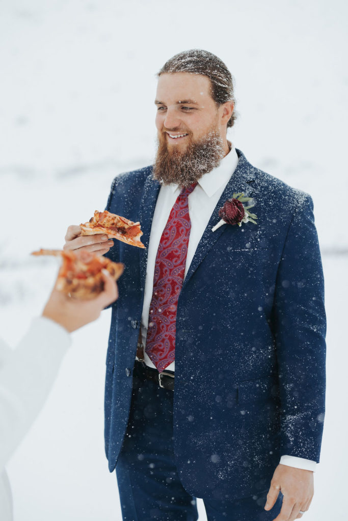 groom eating pizza in the snow