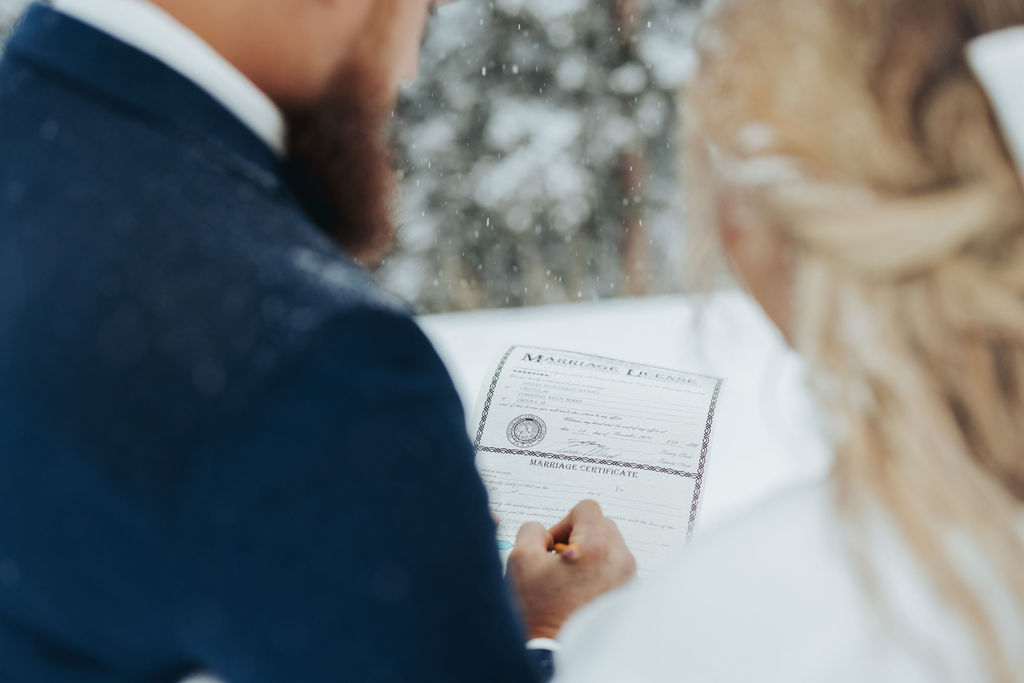 bride and groom signing marriage license snowy mountain elopement