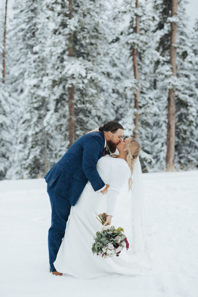 Bride and groom kissing snowy mountain elopement