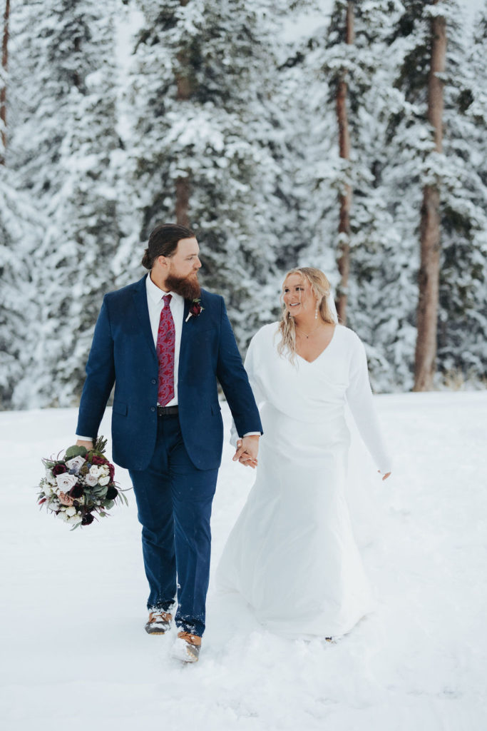 Bride and groom holding hands snowy mountain elopement