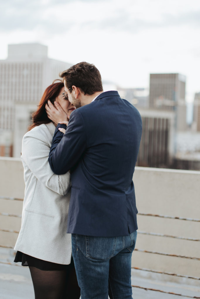 engaged couple kissing on birmingham rooftop
