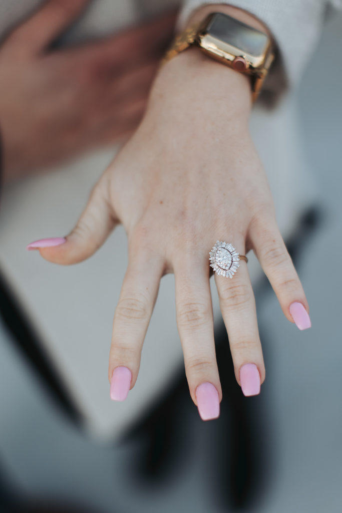 woman with pink nails showing engagement ring
