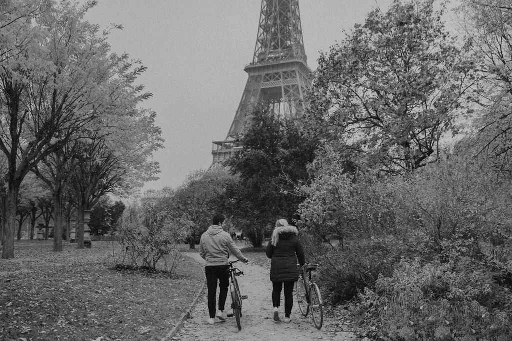 couple walking with bikes in front of eiffel tower