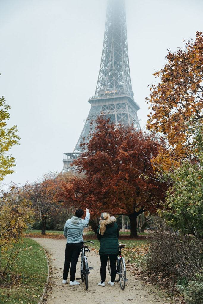 couple holding bikes looking at eiffel tower