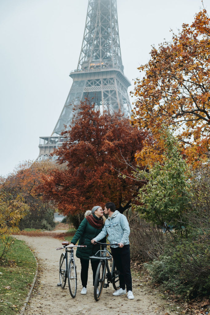 couple kissing in front of eiffel tower and fall trees