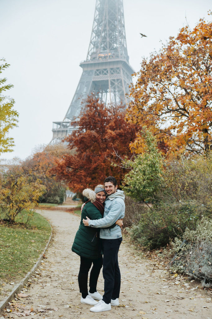 couple hugging in paris france surrounded by autumn leaves