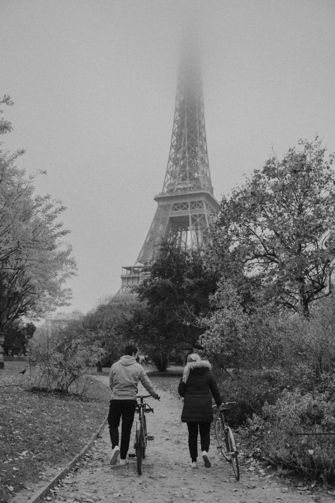 couple walking their bikes towards the eiffel tower