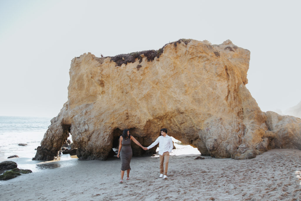 Couple holding hands at the beach california engagement