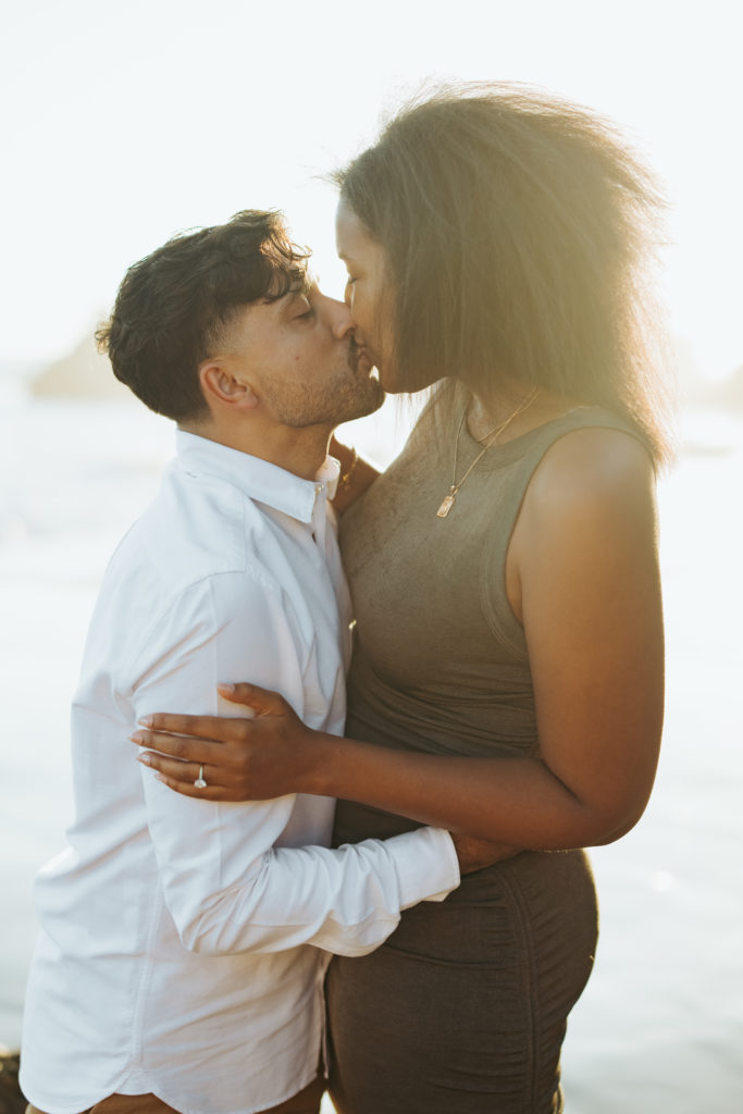 engaged couple kissing on the beach