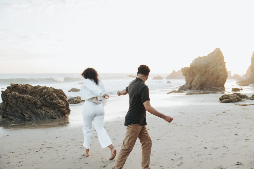 engaged couple running on the beach