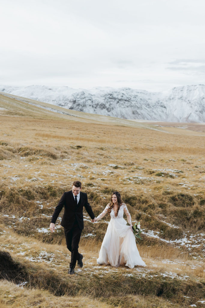 bride and groom walking on snowy mountains iceland elopement