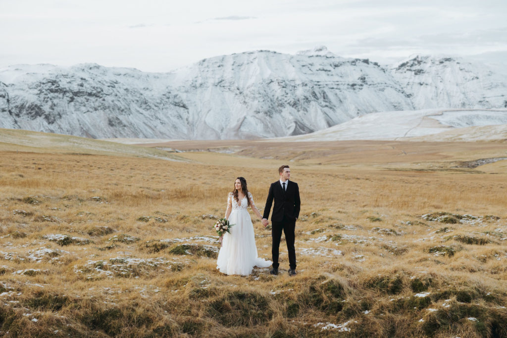 bride and groom walking on snowy mountains iceland elopement