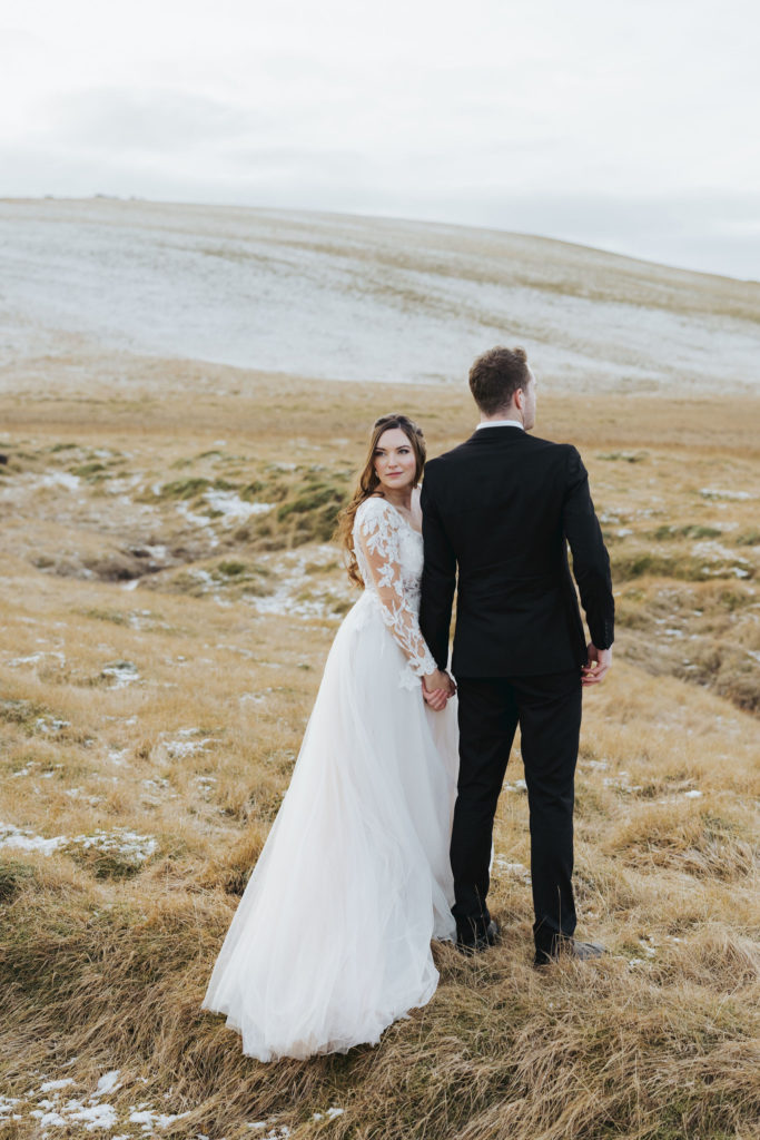 wedding couple during elopement day on snowy mountains in iceland