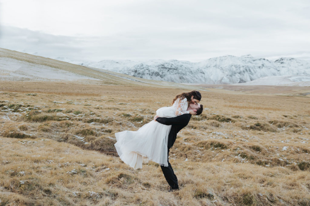 groom picking up bride elopement portraits on snowy mountains in iceland