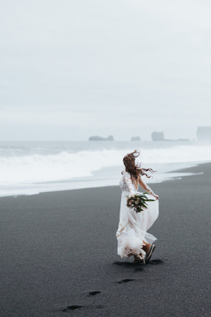 bride walking on black sand beach iceland