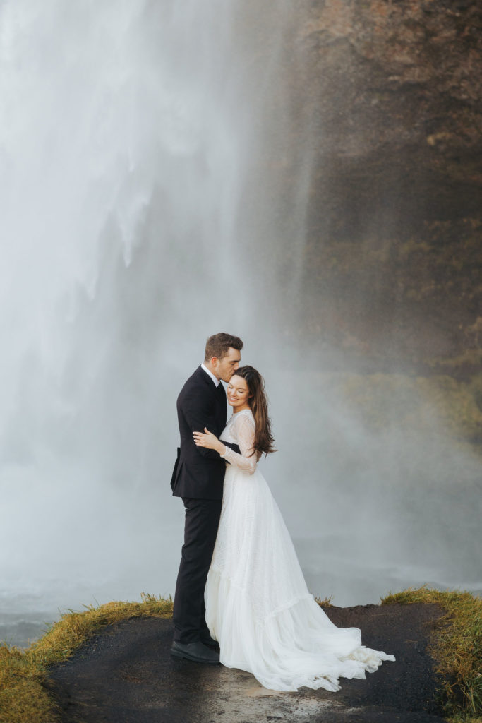bride and groom elopement walking under waterfall in iceland