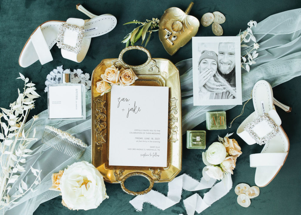 nashville wedding flatlay with manolo shoes, rings, perfume, and invitation