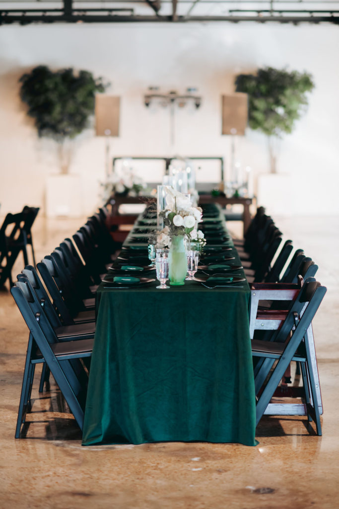 velvet green table runner with black chairs at wedding reception