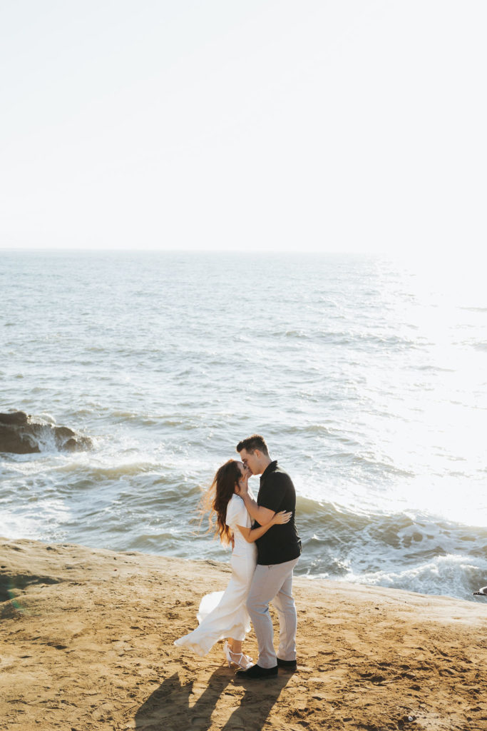 engaged couple kissing at sunset on san diego cliff