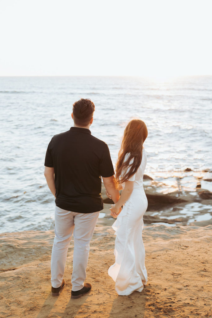engaged couple looking over water on san diego coast
