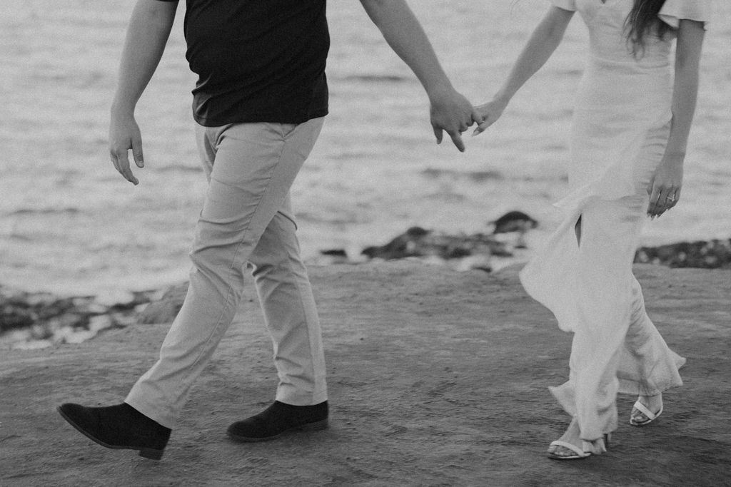 engaged couple holding hands and walking on san diego cliffs