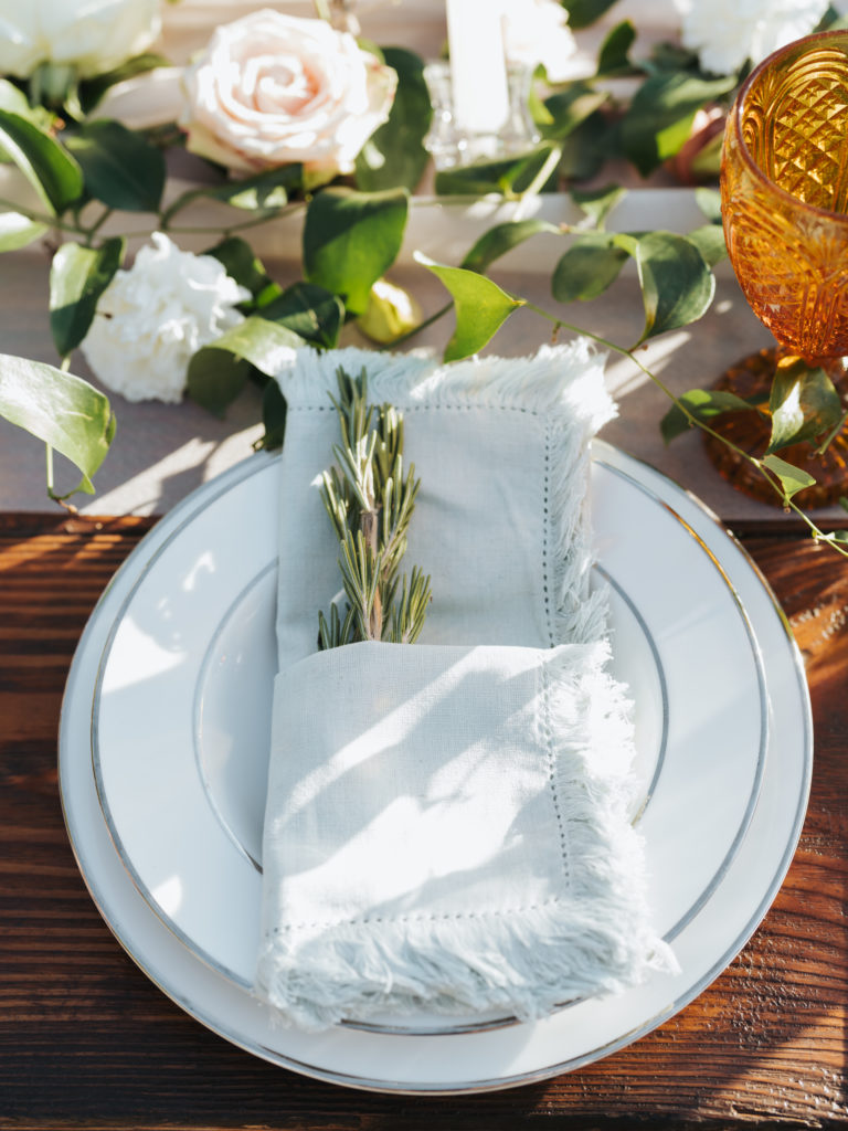 place setting with white linen napkin and rosemary