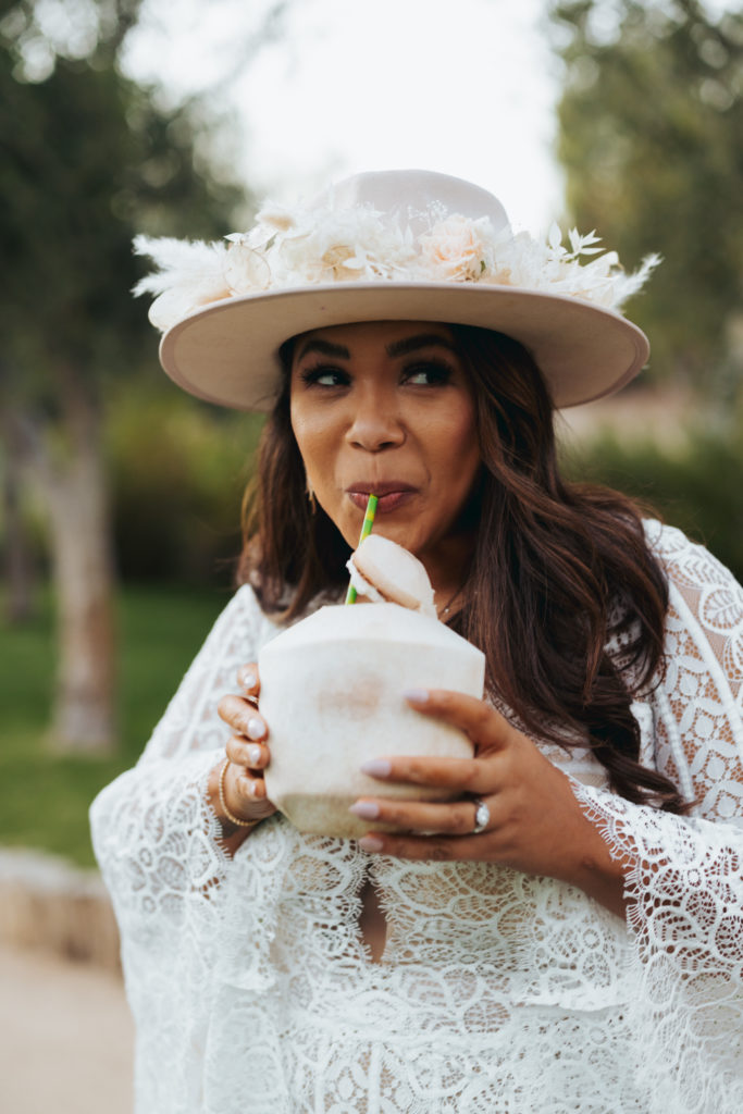 bride drinking water from coconut wearing floral hat