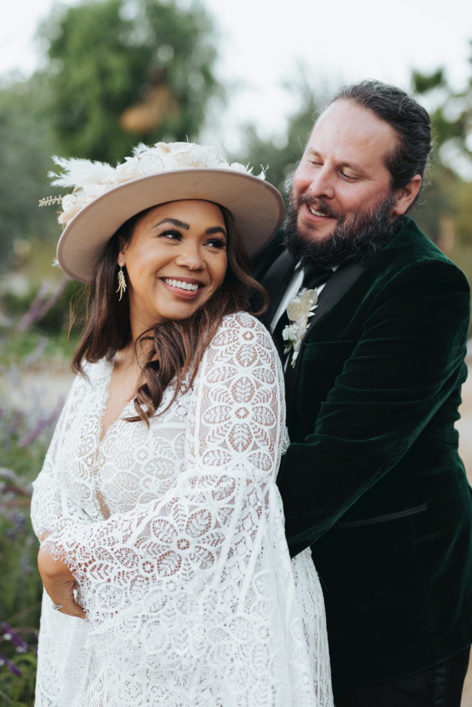 bride wearing floral hat with groom in green velvet suit