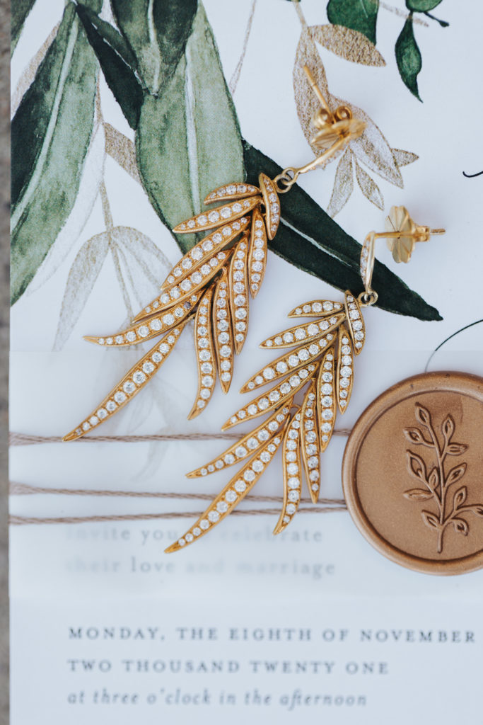 gold leaf earrings on wedding invitation suite