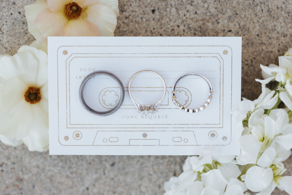 wedding rings displayed on song request card with flowers