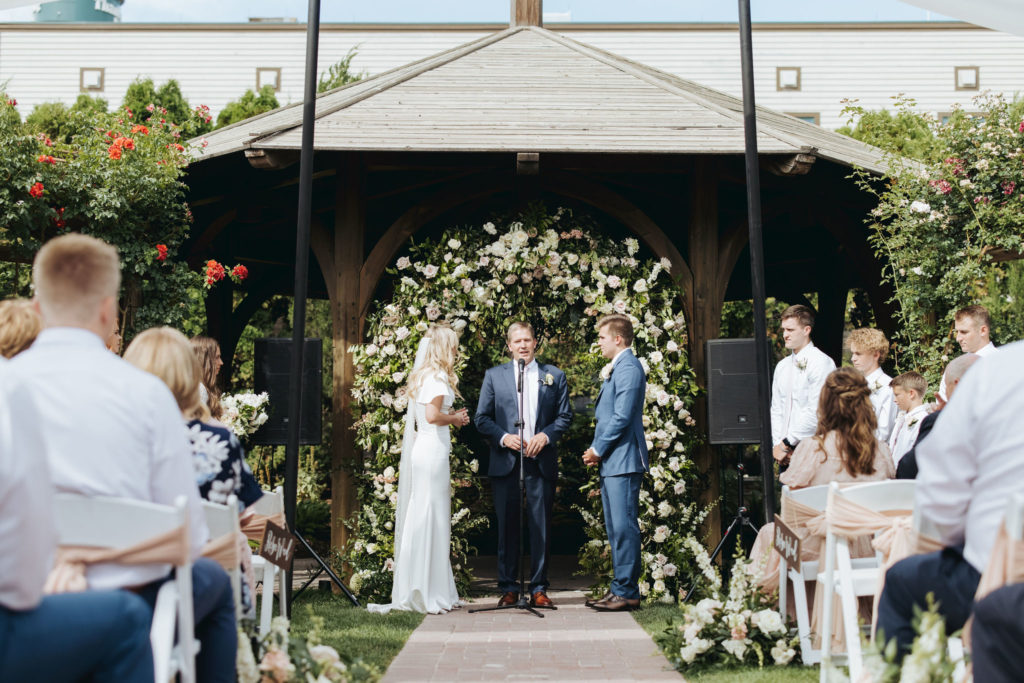 bride and groom wedding ceremony under floral arch