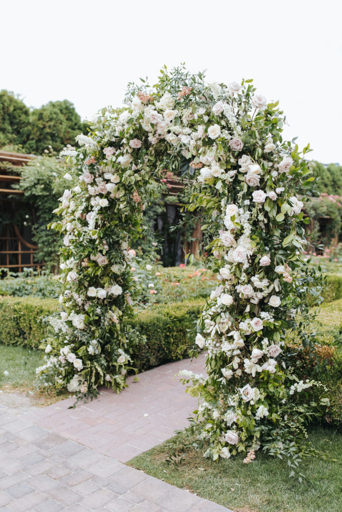 wedding ceremony flower arch with pink and cream flowers and greenery